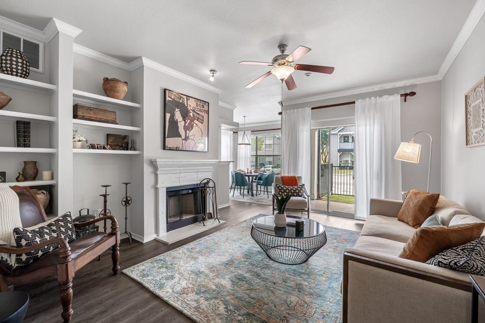 a living room with a couch, chair, coffee table, fireplace, and ceiling fan at Marquis at Lantana in Flower Mound, TX.