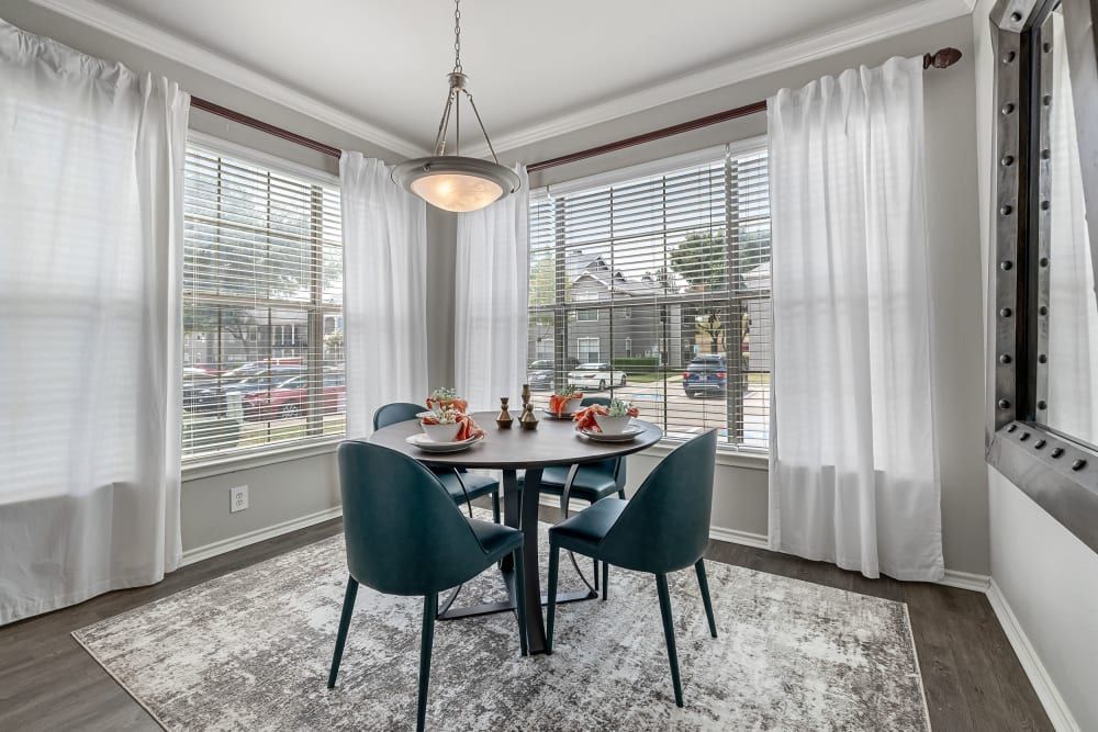 a dining room with a table and chairs and lots of windows at Marquis at Lantana in Flower Mound, TX.