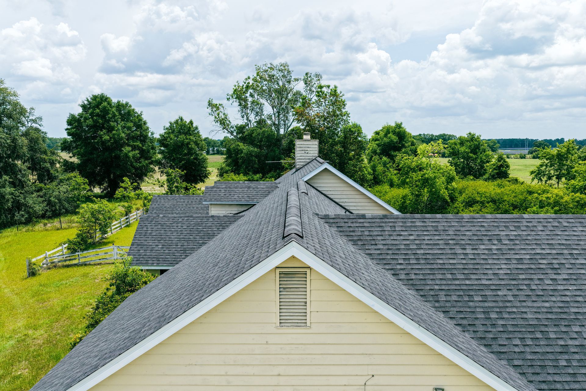 High-angle drone view of a well-maintained grey shingle roof on a Florida home, showing clean gutter