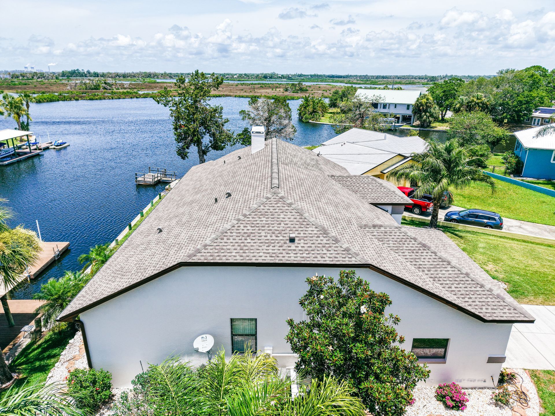 Professional inspector in orange safety gear examining a Florida residential roof under mixed sun an