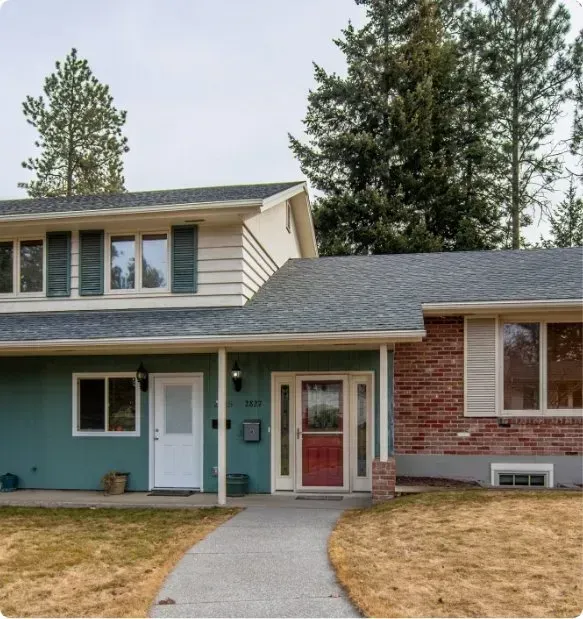 A green house with a red door and a white door