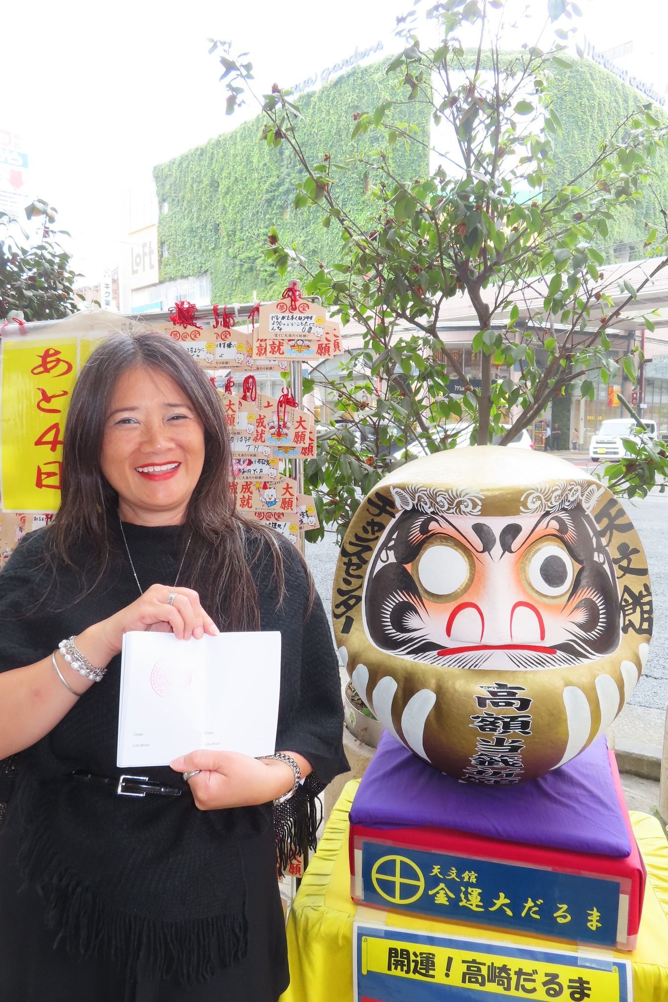 A woman is holding a piece of paper in front of a large statue.