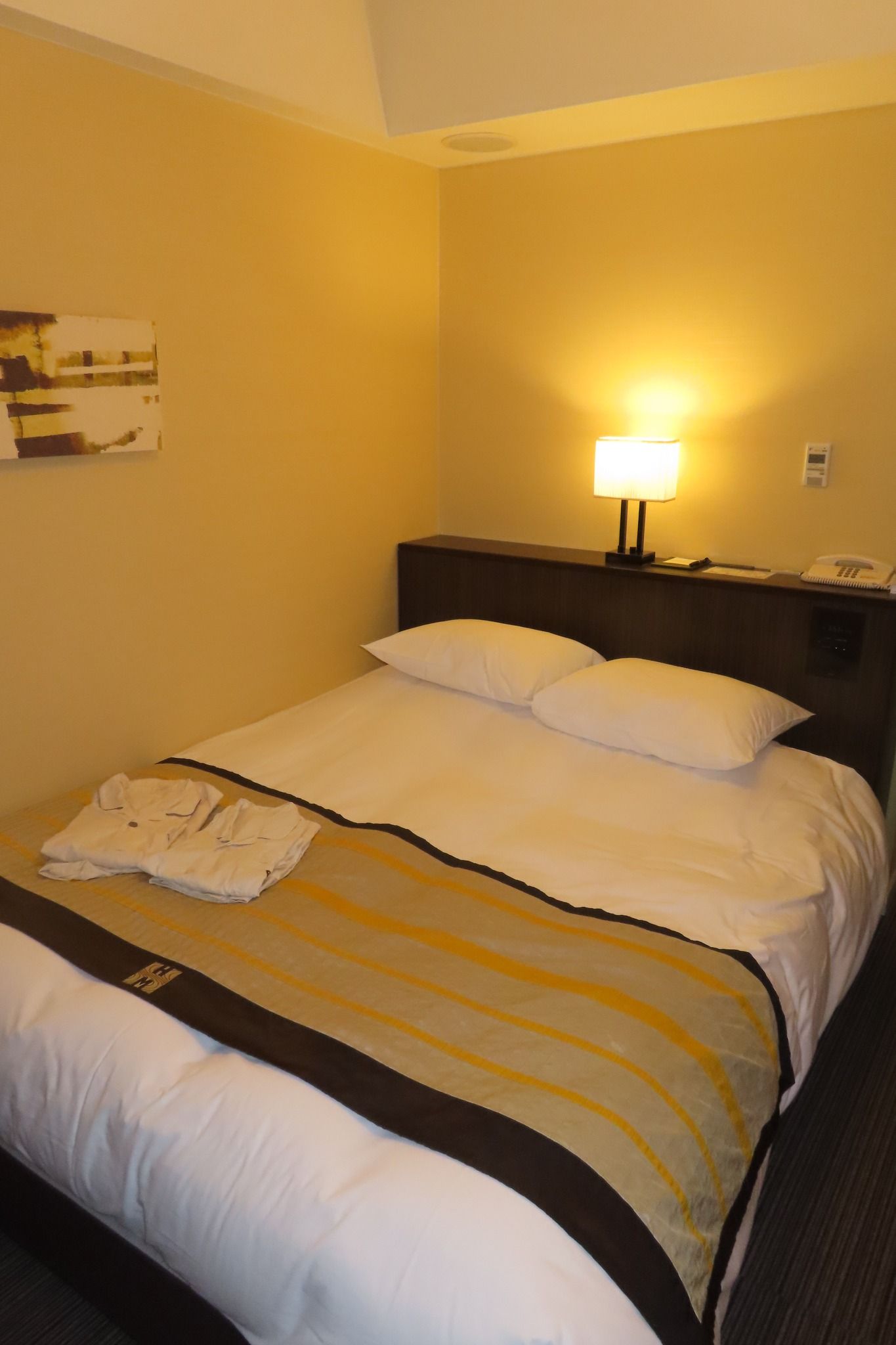 A hotel room with a bed and a lamp