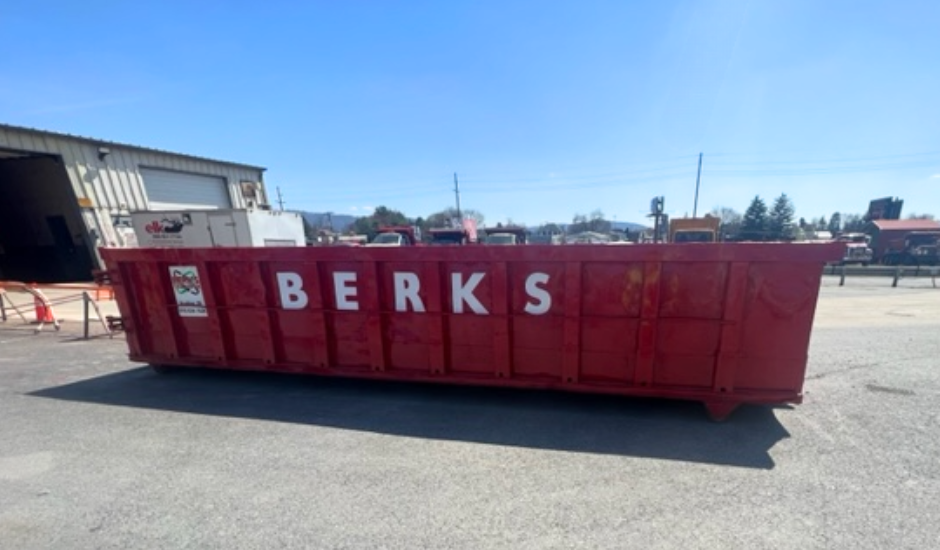 A large red dumpster with the word Berks on it