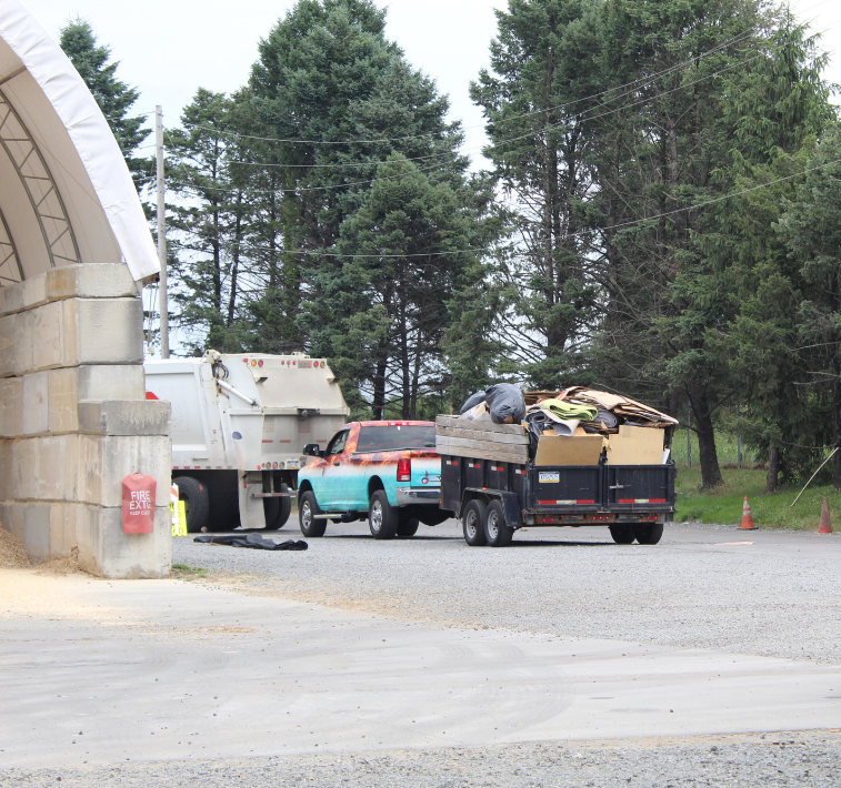 A white truck is backs into the warehouse to unload trash.