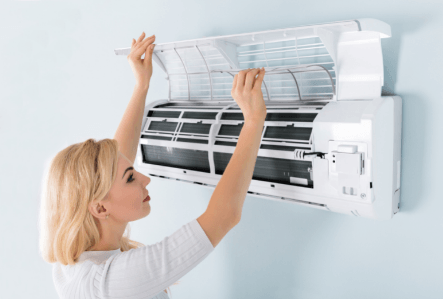 Picture of a woman checking the filter in a ductless heat pump unit.