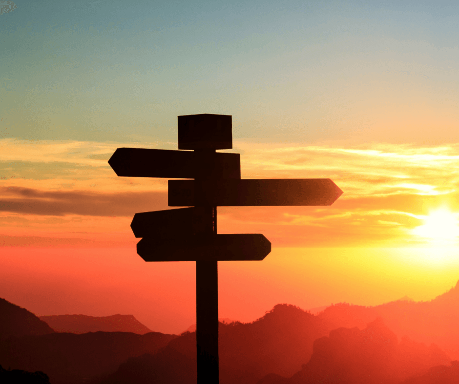 Photo of cross road signs with a sunset in the background.