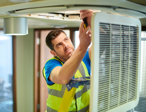 Close up photo of a professional technician inspecting a celling while wearing a yellow visibility vest.