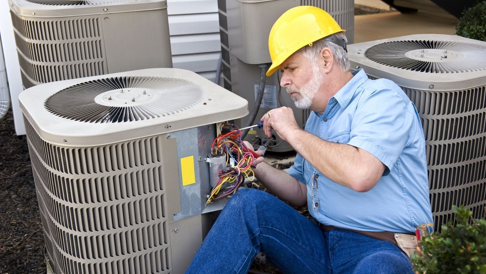 Picture of a repair man working on a heat pump outside.