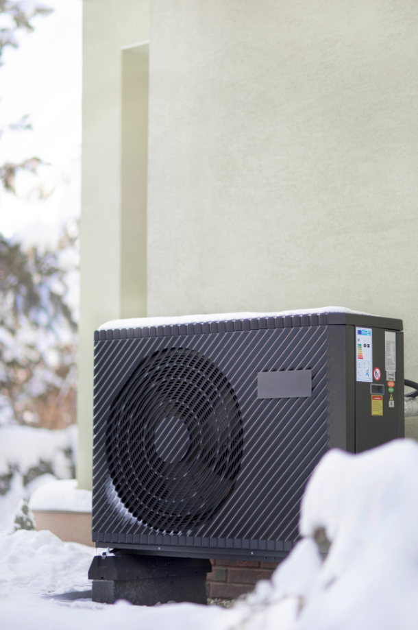 Heat pump standing against a wall during winter