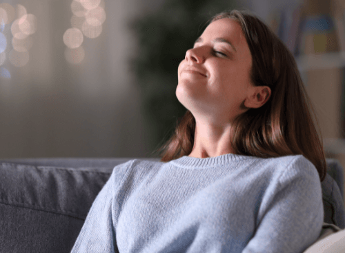 Picture of a woman inside breathing deep with her eyes closed.