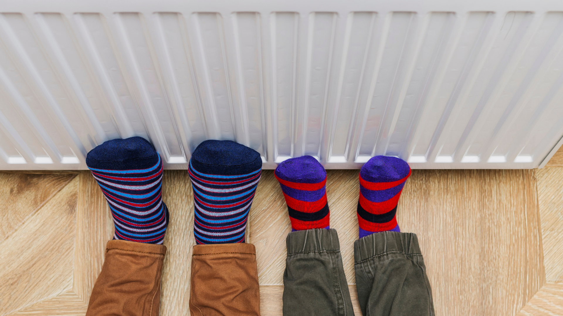 Picture of two sets of kid feet against a wall heater.