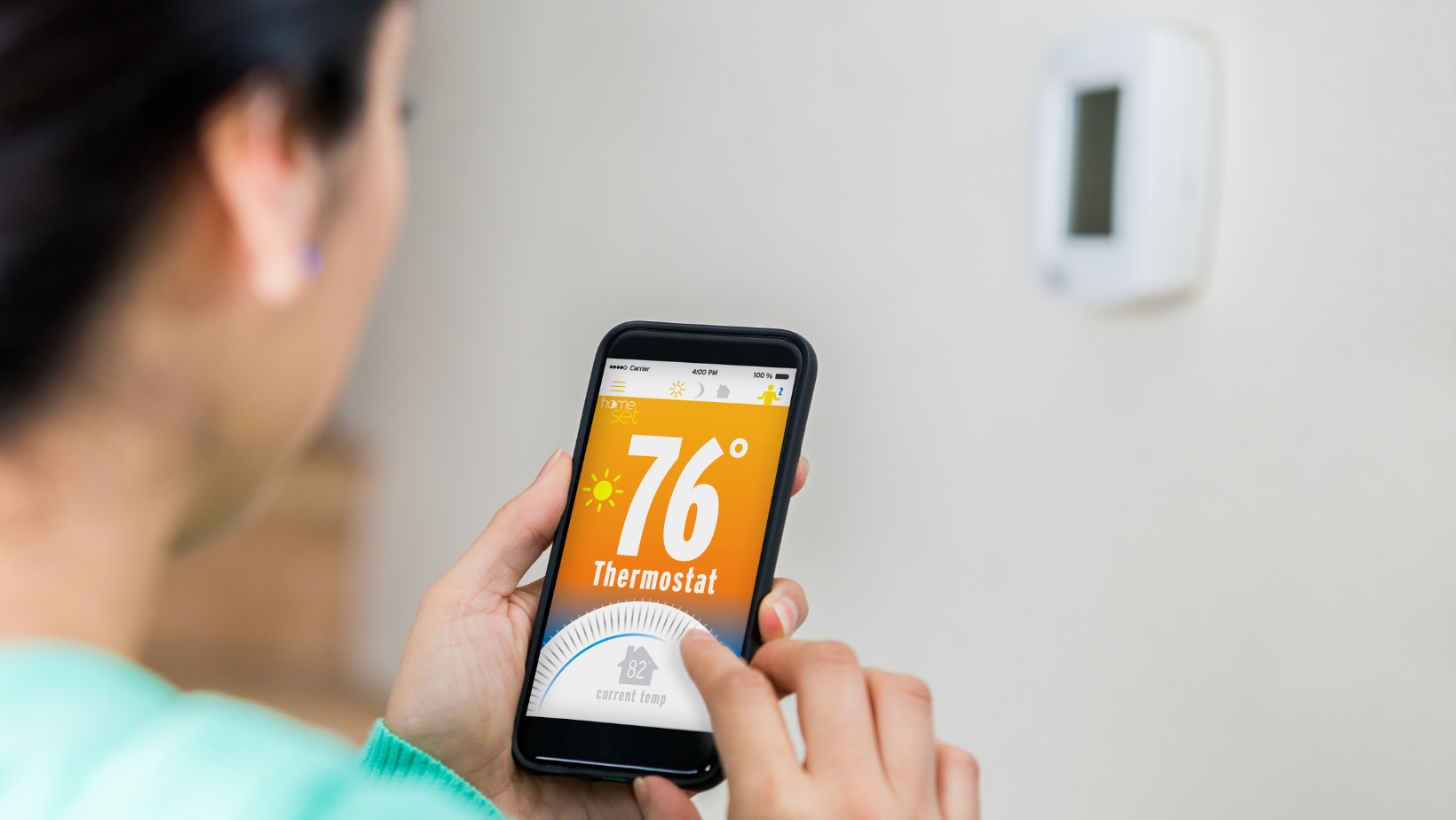 Woman uses smart phone to control thermostat