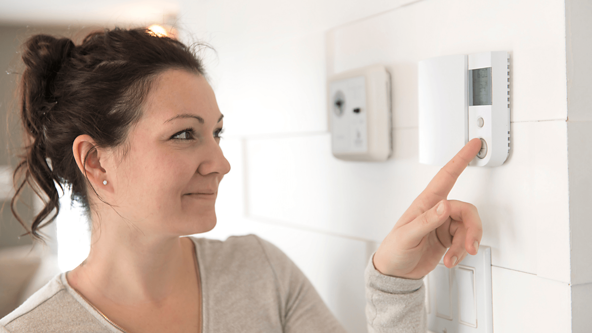 Picture of a woman reprograming her digital thermostat.