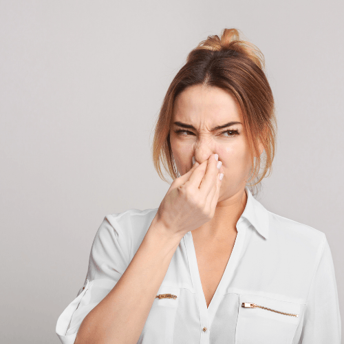 Picture of a woman holding her nose because of a bad smell.