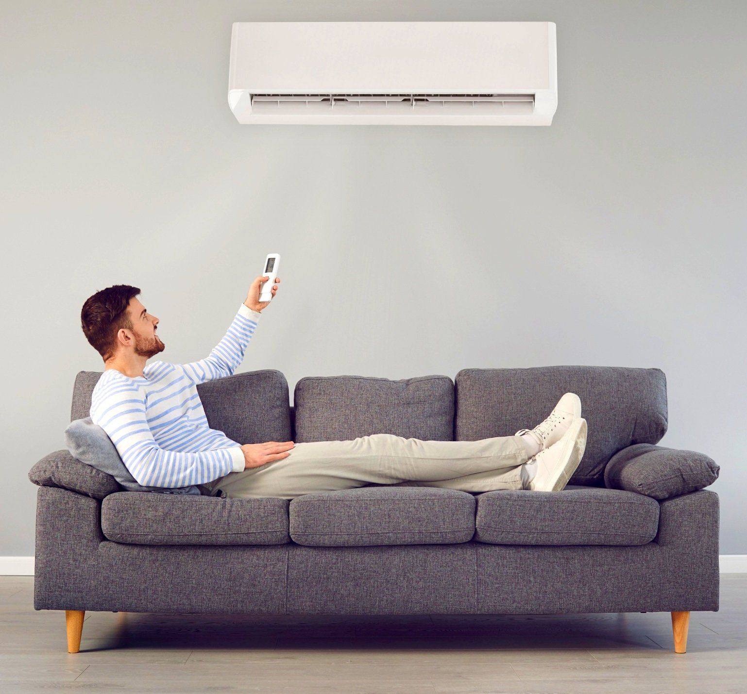 A guy comfortably relaxing in his living room with the air condition on