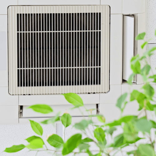 HVAC on a house with tree leaves in front of it