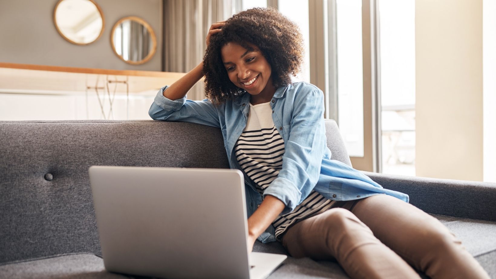 Picture of a woman sitting on her couch with a laptop.