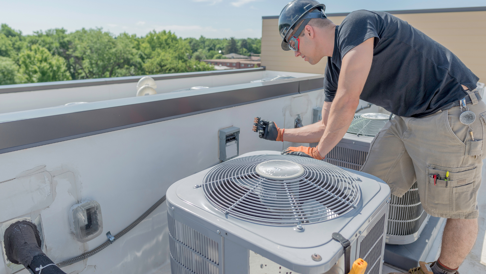 Picture of a man working on an HVAC system on a roof.