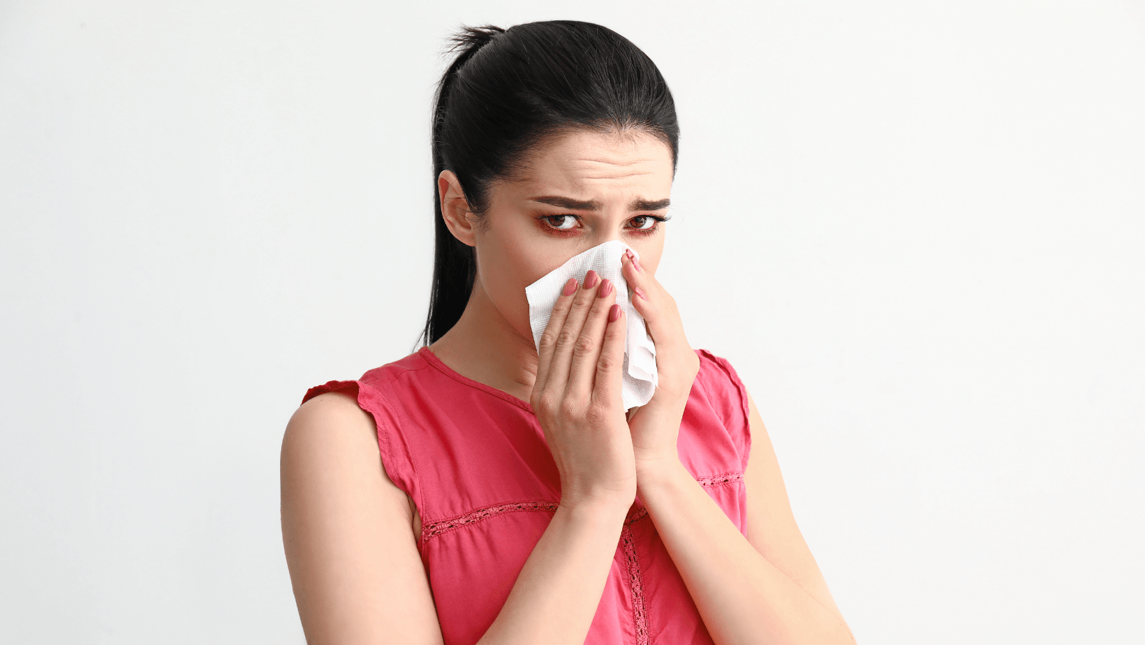 Picture of a woman blowing her nose looking sad.