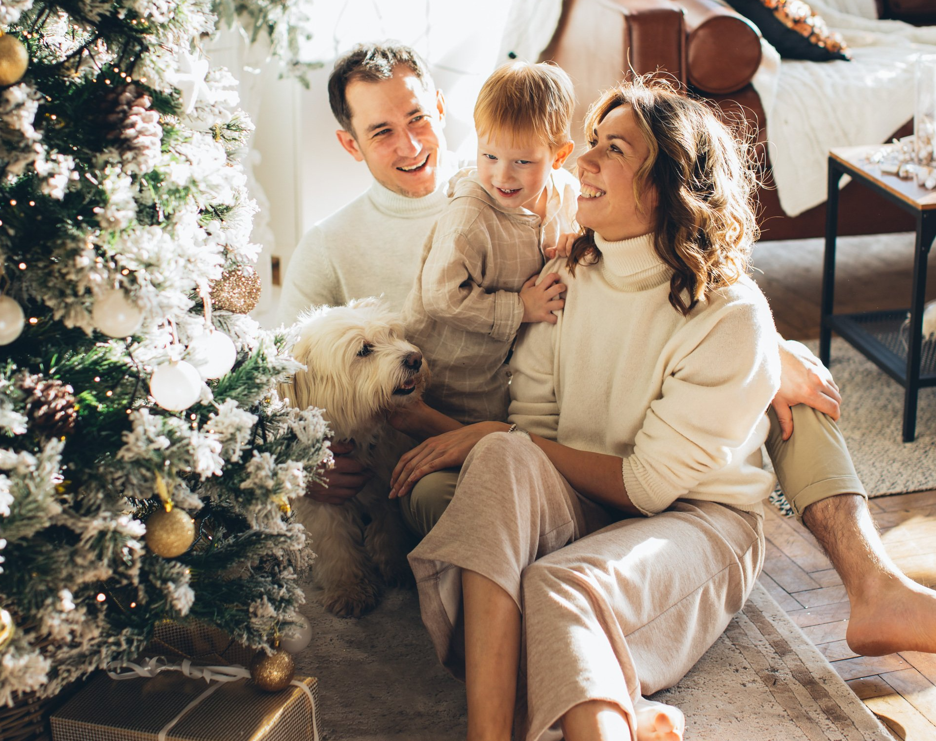 Picture of a family sitting next to a Christmas tree.