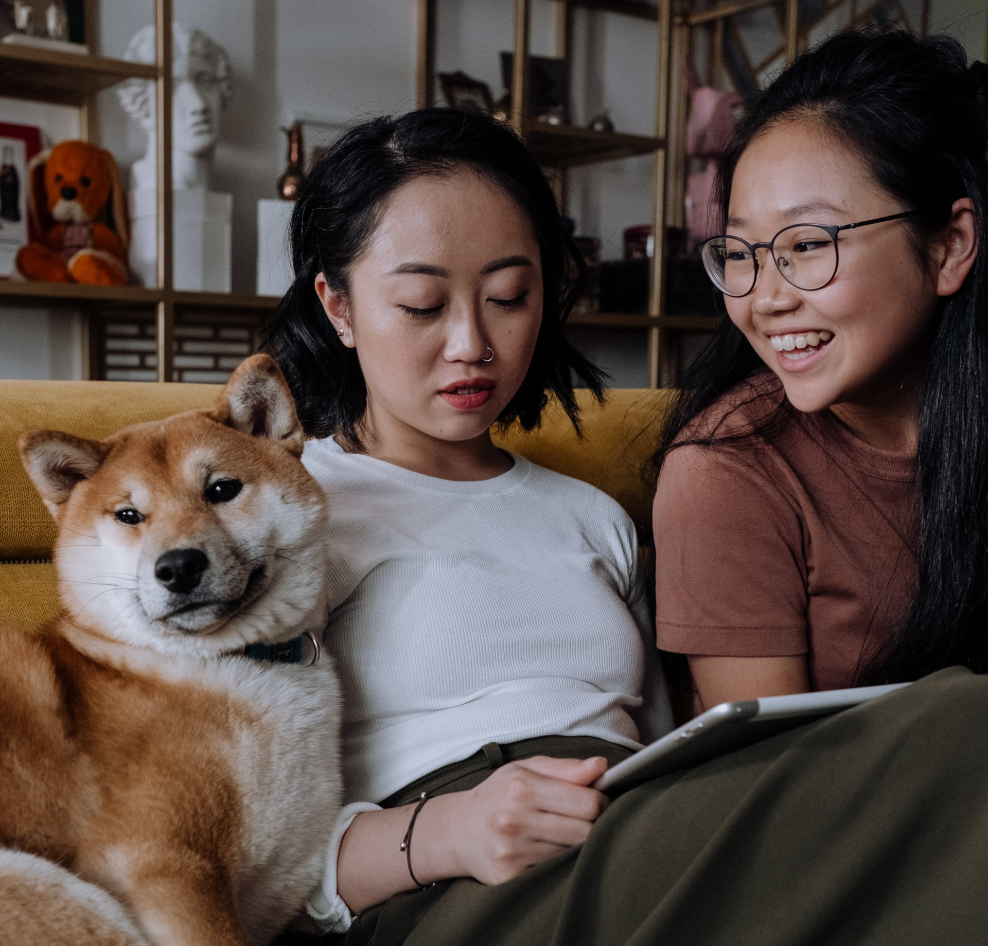 Picture of two girls sitting on a couch with their dog.