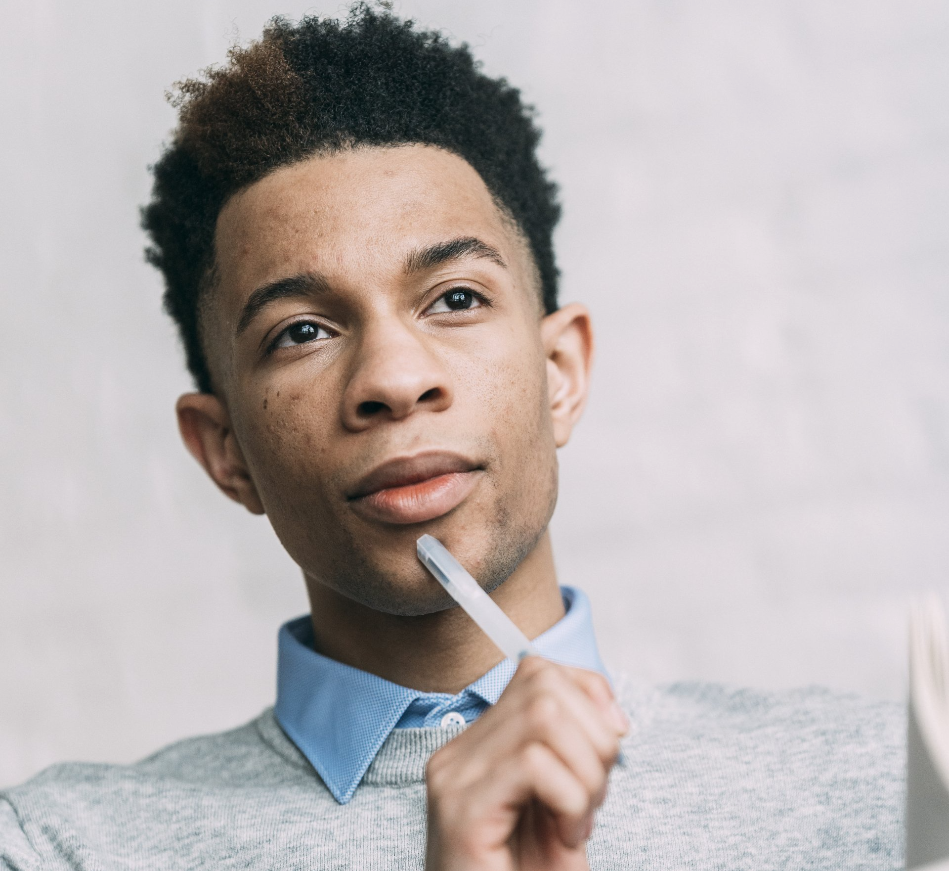 Picture of a man thinking with a pen on his chin.