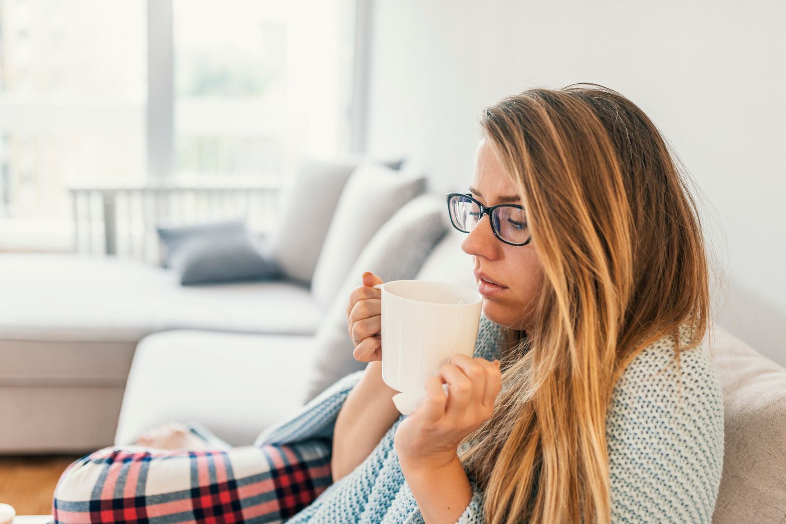 Picture of a woman sitting on a couch holding a cup of coffee