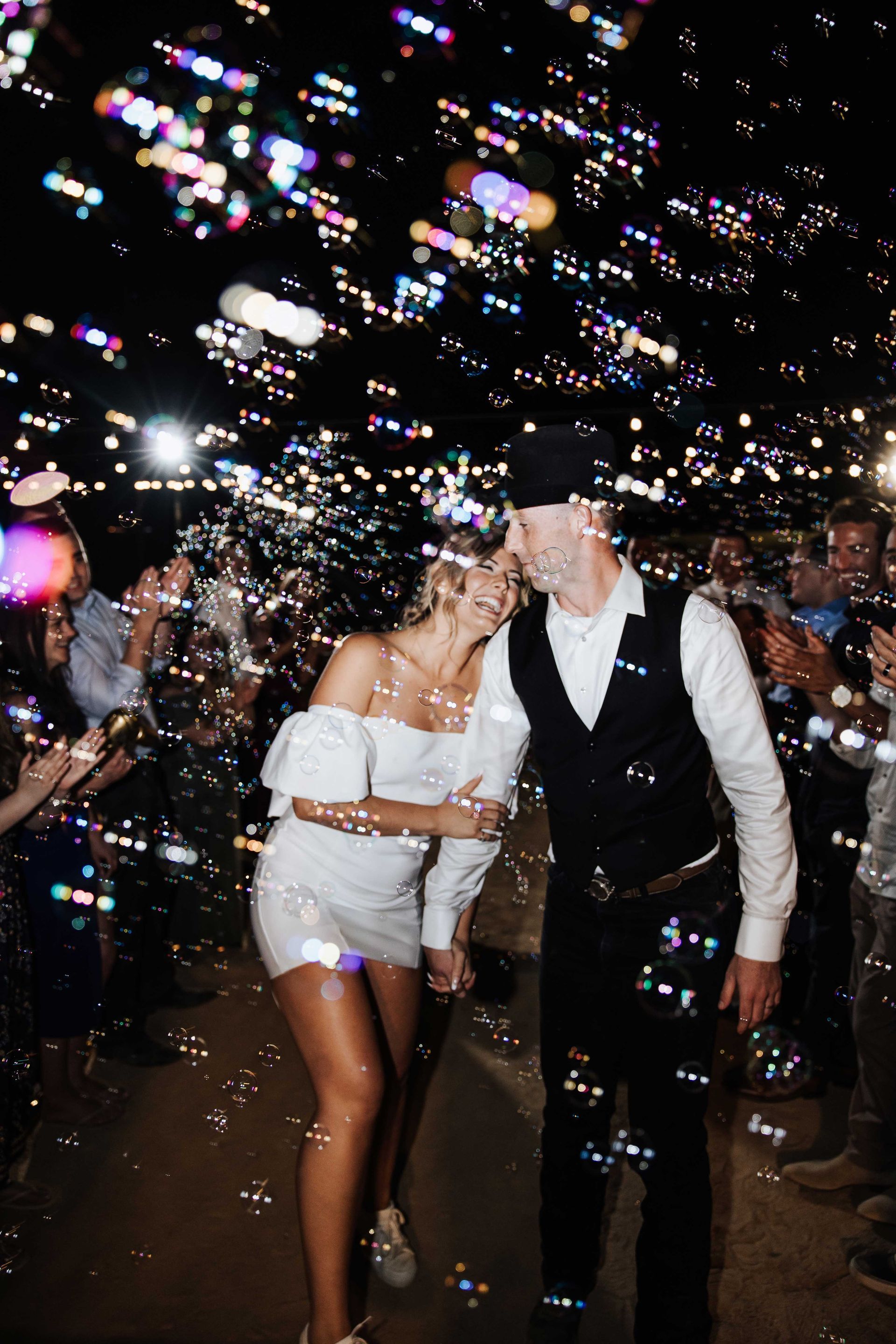 a bride and groom are kissing while surrounded by bubbles
