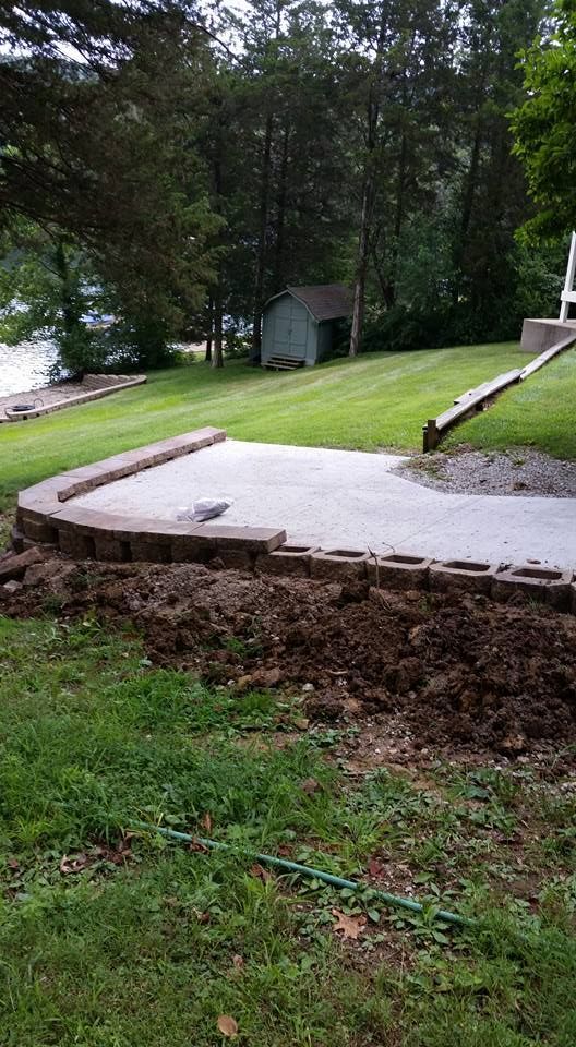 A concrete walkway is being built in the backyard of a house.