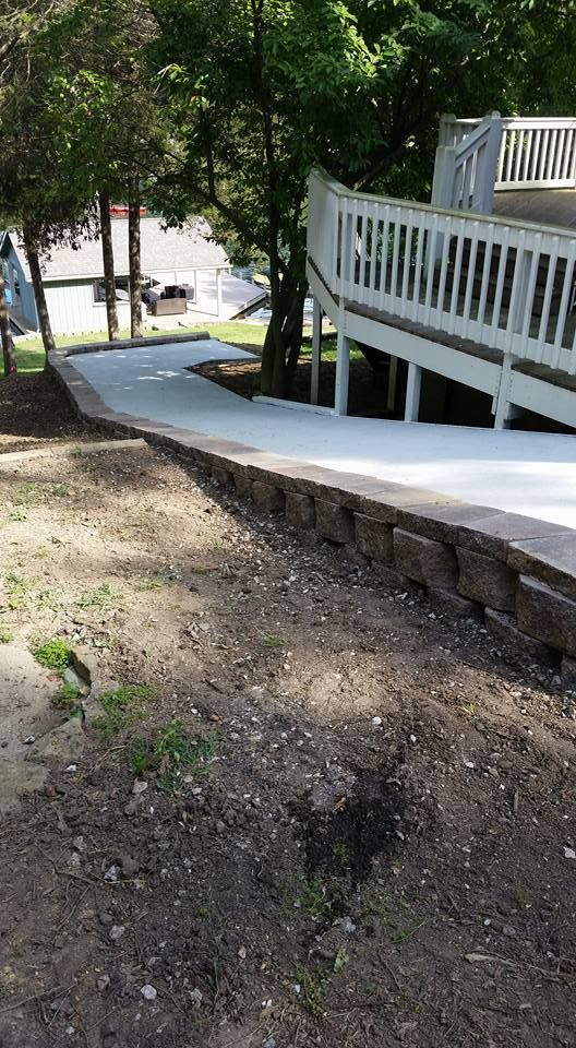 A concrete walkway leading to a deck with a white railing.