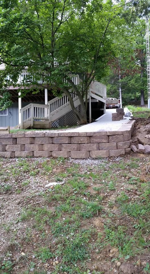 A brick wall is being built in front of a house with a deck.