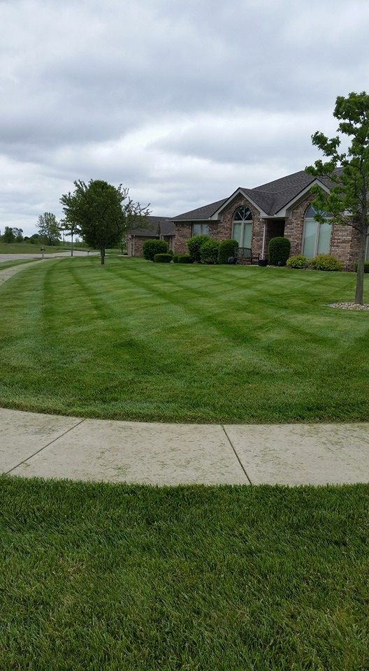 A house with a lush green lawn and a sidewalk in front of it.