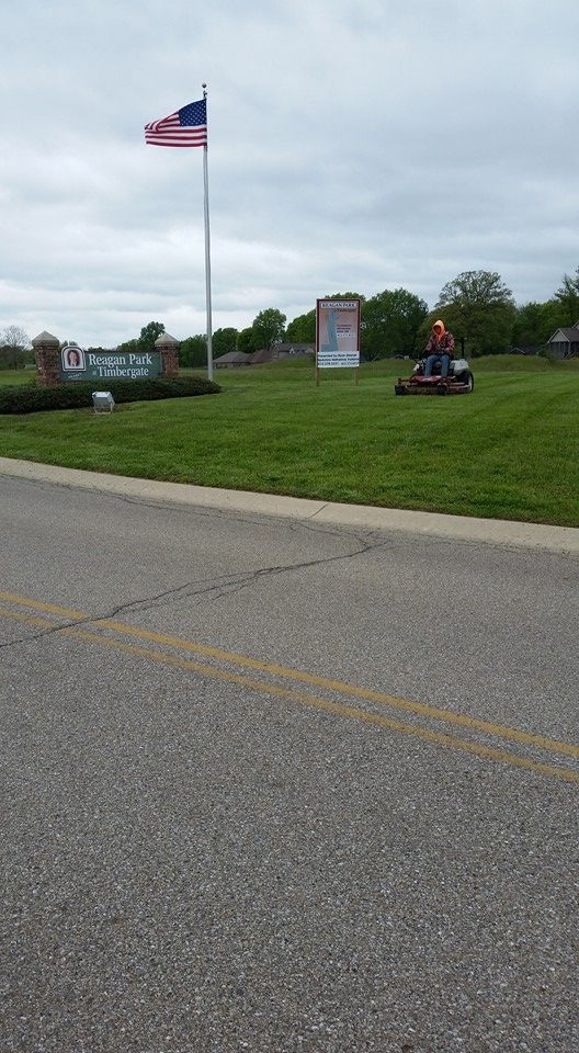 A person is riding a lawn mower on a lush green field.
