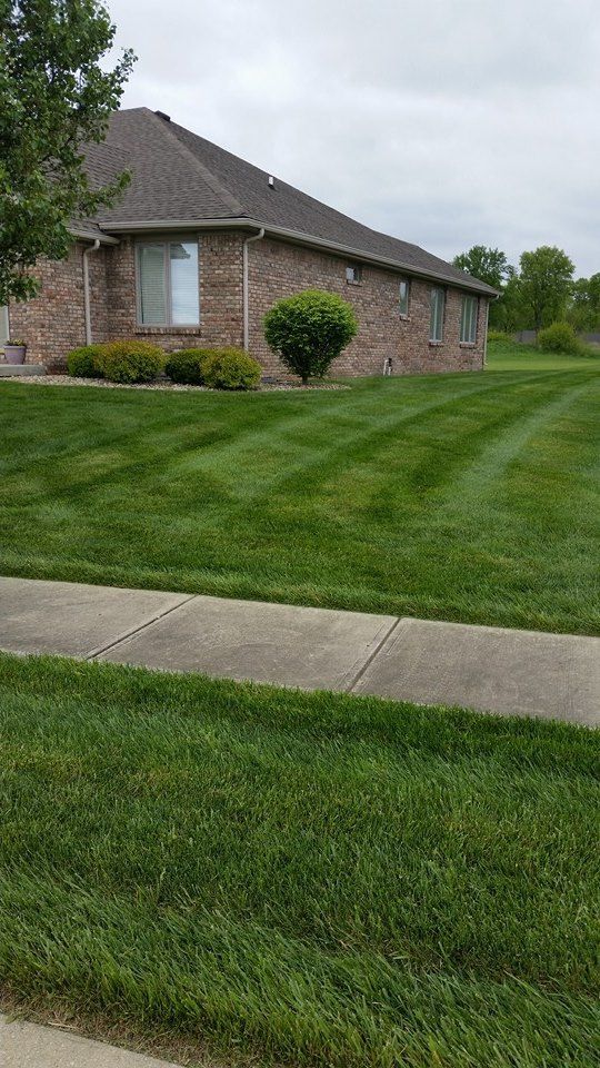 A brick house with a lush green lawn in front of it.