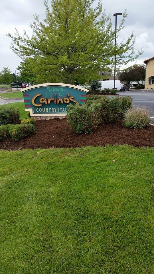 A large sign in the middle of a lush green field.