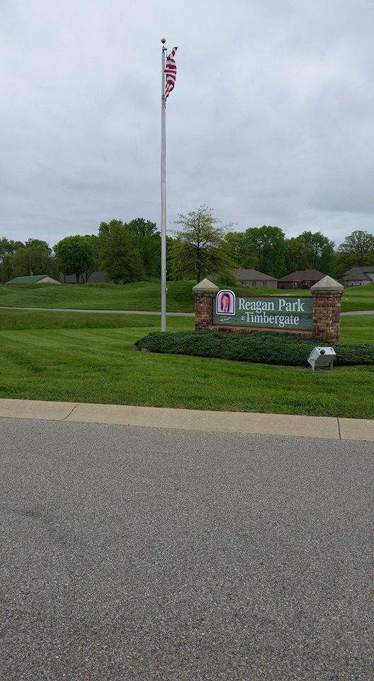 A flag is flying in the wind in front of a sign.