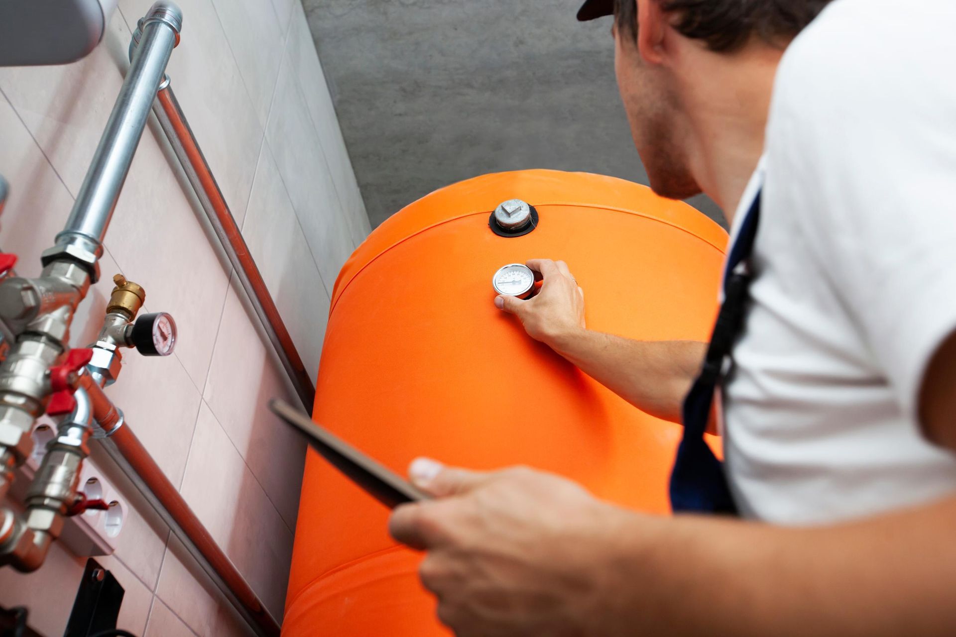 A man is looking at an orange tank while holding a tablet.