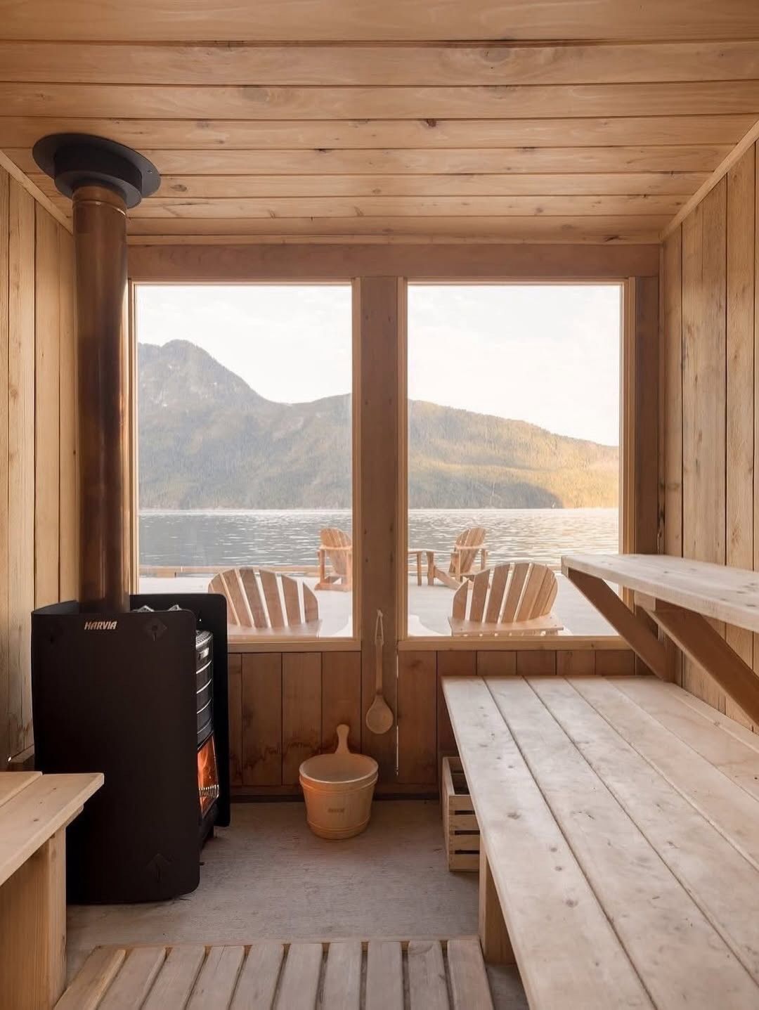 Sauna met houten lambrisering, banken, glazen deuren en uitzicht op de bergen.