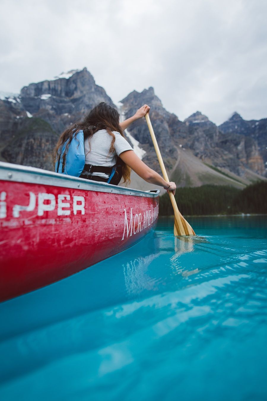 Banff & Lake Louise Tourism (BLLT) / Jake Dyson Vrouw peddelt in een rode kano op turquoise water, met bergen op de achtergrond.