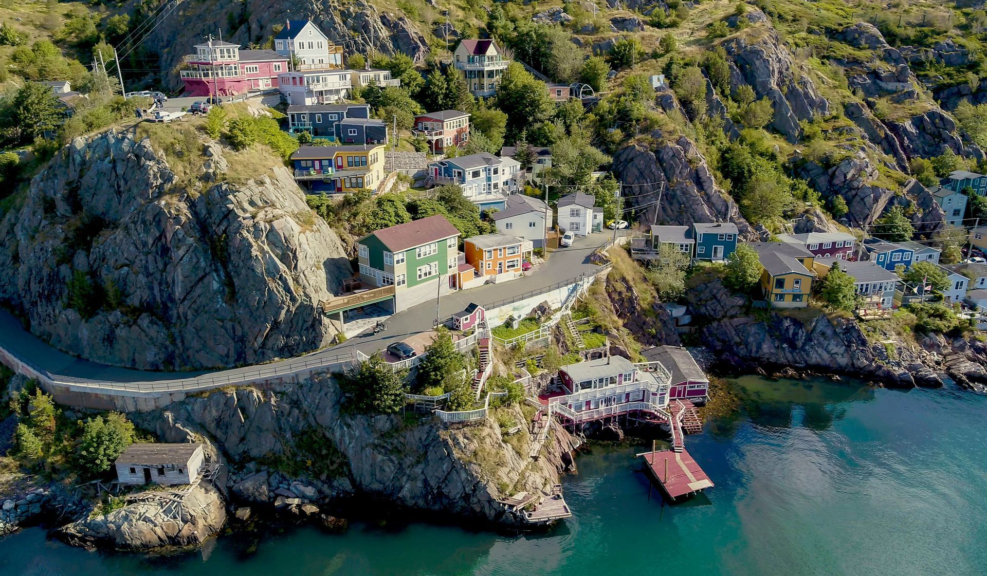 Colorful houses on a hillside overlooking a harbor with a road winding by.