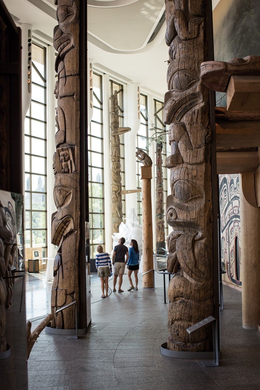 @Destination Canada Museum interior with carved wooden totem poles and visitors.