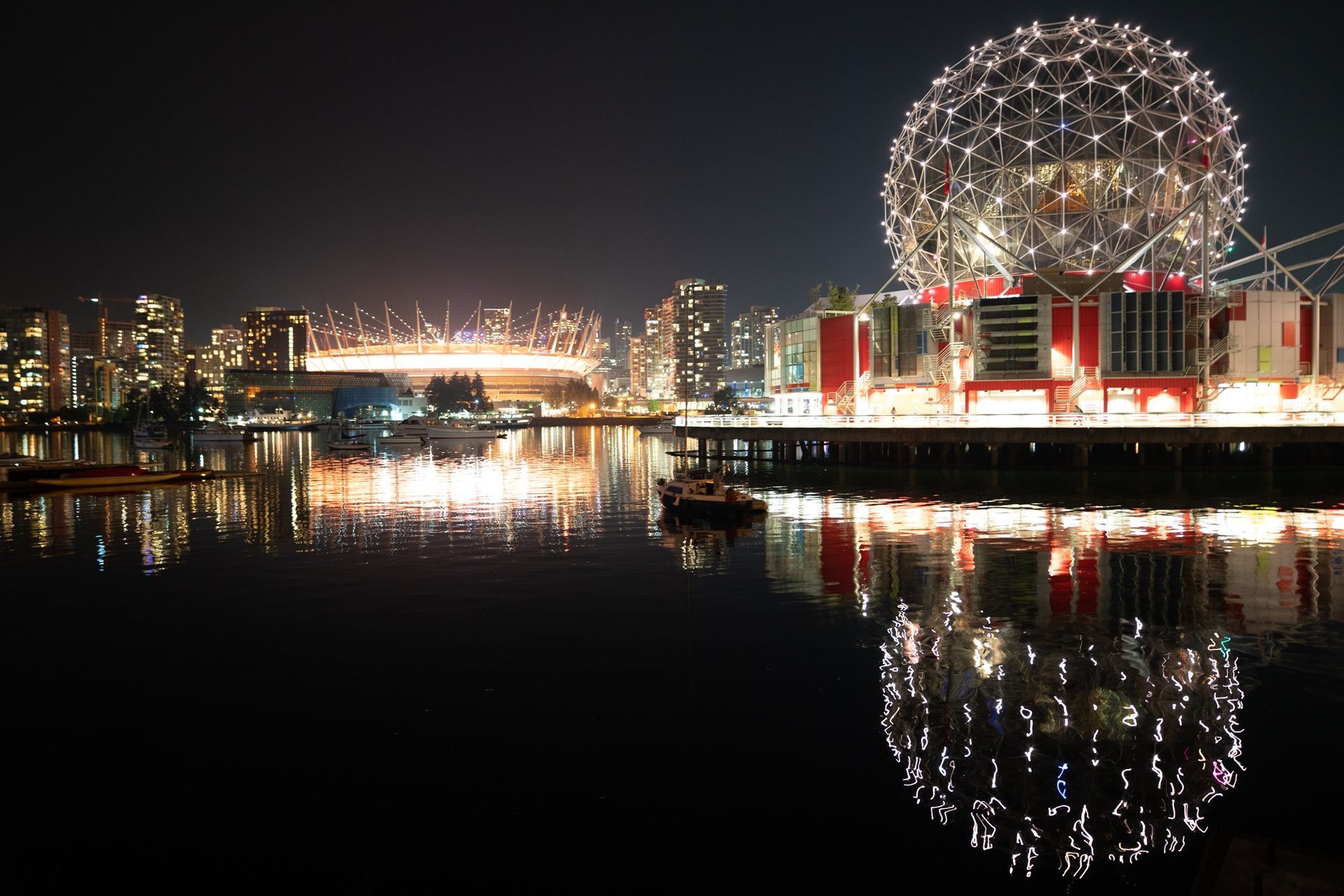@Momme Halbe Destination Canada Science World en de skyline van de stad 's nachts, weerspiegeld in het kalme water.