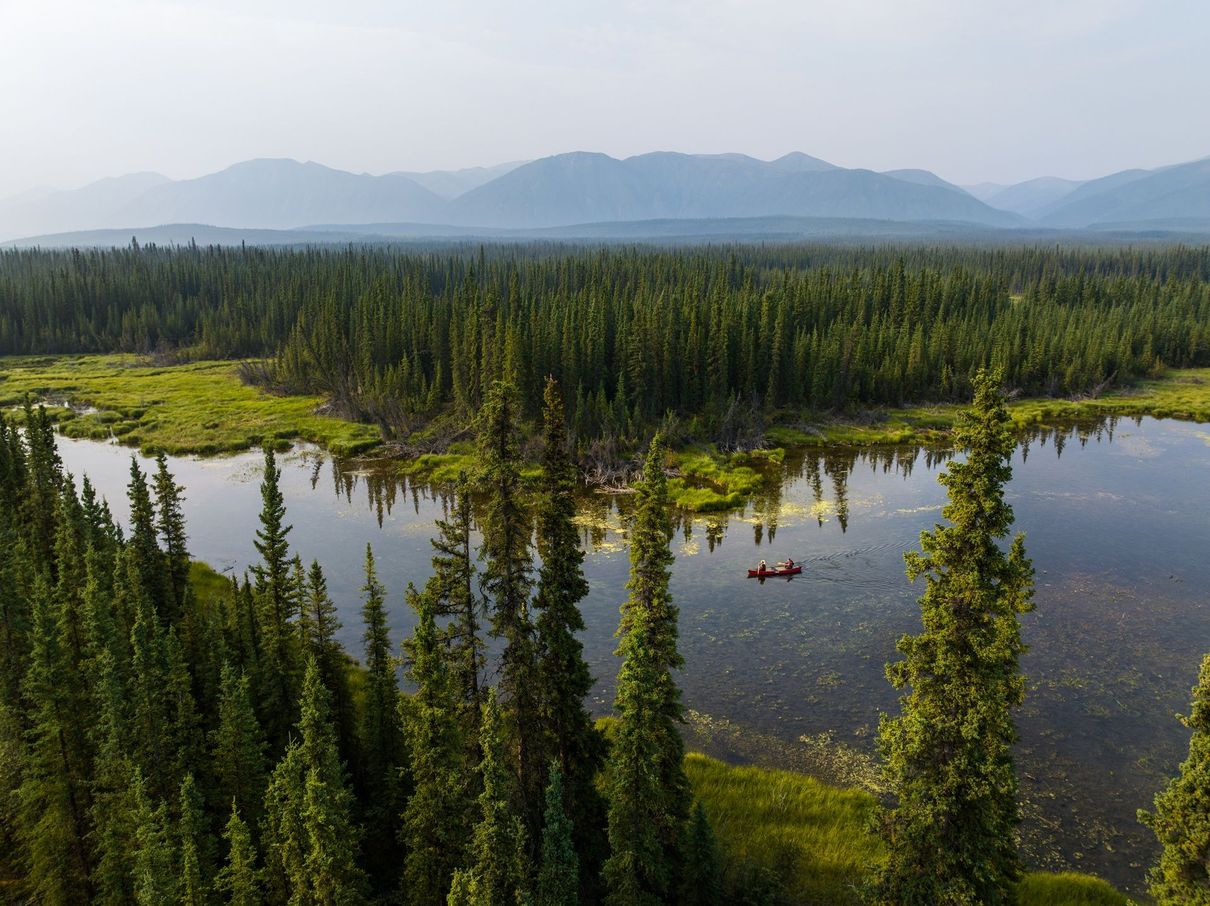 Verbluffend landschap in Noord Canada Luchtfoto van een bebost meer met bergen in de verte en helderblauw water.