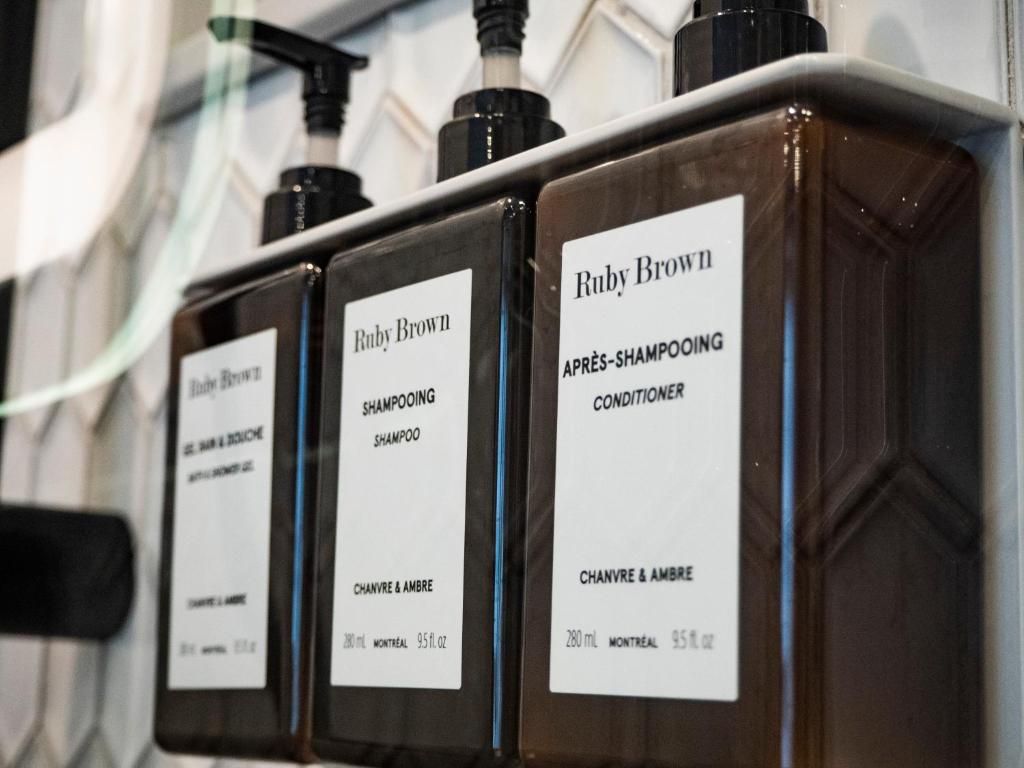 Op een aanrecht staan ​​drie donkerbruine pompflessen met witte etiketten, waarschijnlijk haarverzorgingsproducten.