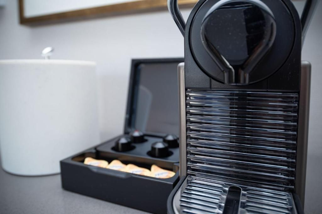 Een zwart koffiezetapparaat met kopjeshouder op het aanrecht, naast een bakje met koffiecups.