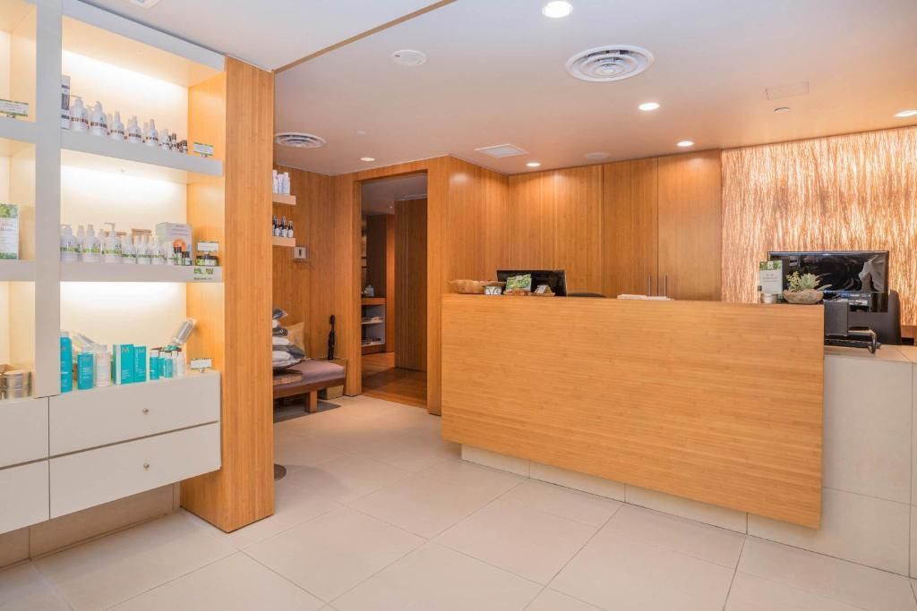 Moderne spa-receptie met houten balie, vitrines en een licht, minimalistisch interieur.
