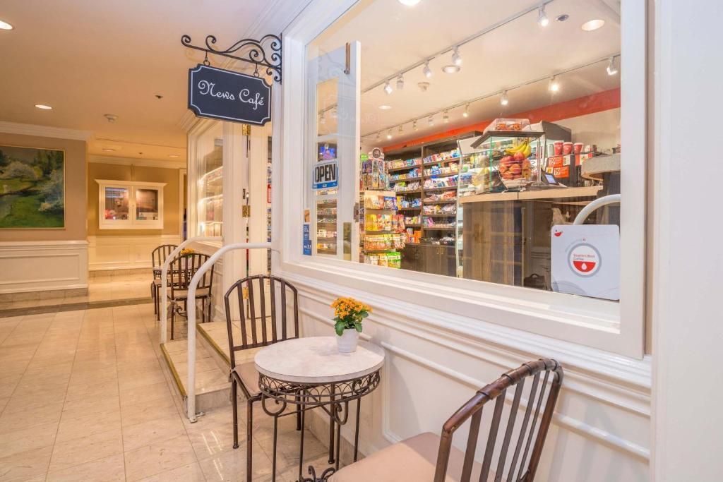 Terrasjes naast de etalage van een patisserie, met kleine tafels, stoelen en sfeervolle lichtslingers.