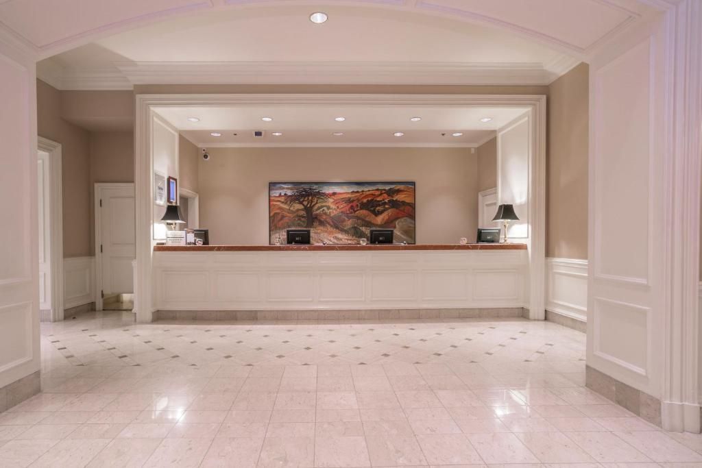 Elegante hotellobby met marmeren vloer, inbouwverlichting en een lange receptiebalie onder abstracte kunstwerken.