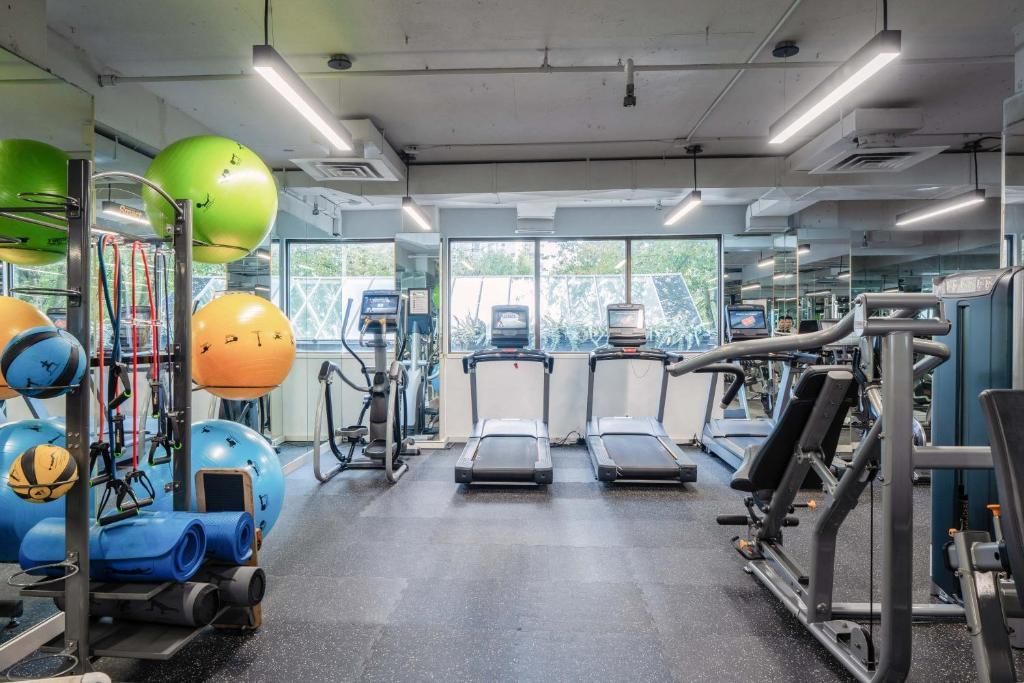 Moderne sportschool met loopbanden, gewichtsapparaten en kleurrijke oefenballen in een lichte studio.